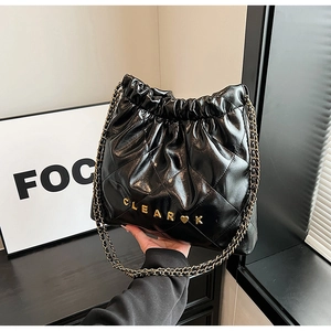 Close-up of black quilted leather drawstring bucket bag with gold chain strap