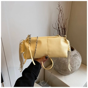 Detail of pale yellow pleated baguette bag featuring long tassels and silver chain strap