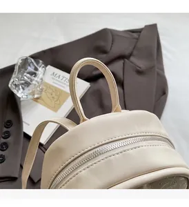 Détail de la poignée supérieure et de la fermeture éclair en métal argenté du sac à dos