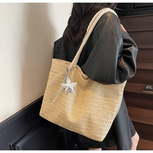 Close-up of woven straw tote bag with braided rope handle and silver star charm detail