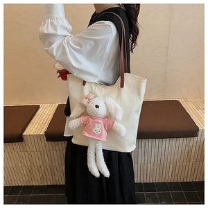 Dettaglio della borsa tote bianca con simpatico coniglio di peluche e manici in pelle marrone