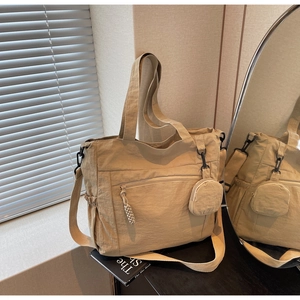Detail of beige nylon tote bag with pleated texture, zipper pocket and small round pouch
