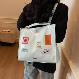 Minimalist mint green large capacity tote bag with cartoon patches worn by model