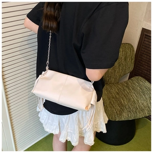 Detail view of the cream pleated baguette bag with long side fringes and silver chain strap
