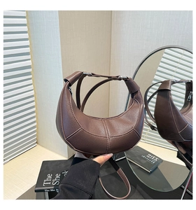 Detailed view of the brown crescent moon bag showing premium pebbled leather and silver hardware