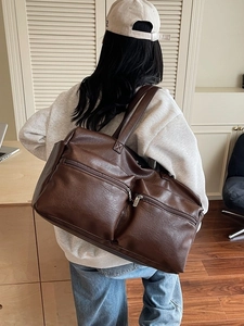Large dark brown PU leather tote travel bag with dual zipper pockets shown on model