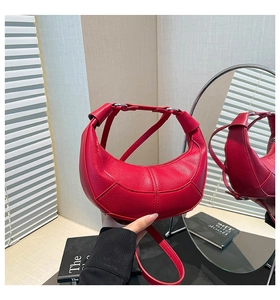 Detail of red crescent bag showing lychee grain texture and silver metal hardware