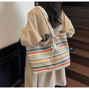 Detailed view of rainbow striped woven tote bag with white rope straps and star charm