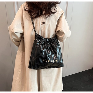 Detail of black quilted bucket bag with gold chain strap and metal logo lettering
