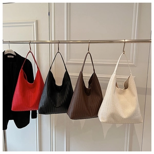 Row of woven leather tote bags in red, black, brown and cream on hanging display