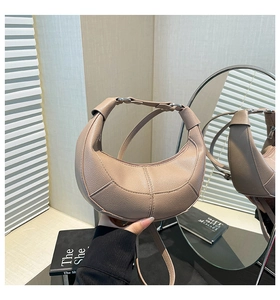 Detailed macro view of beige crescent bag with lychee grain leather and silver hardware