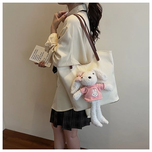 Dettaglio borsa tote intrecciata bianca con cinturini in pelle marrone e ciondolo a coniglio