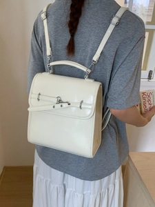 Minimalist creamy white leather backpack with silver rings shown on a model's back