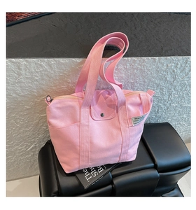 Detail view of the pink canvas tote bag showing the shoulder strap and zipper closure