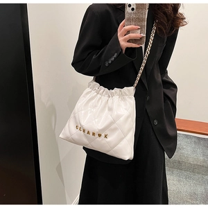 Detailed macro view of white quilted bucket bag with gold Clear K logo and metal chain strap