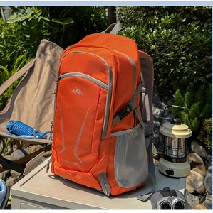 Outdoor 40L backpack detail featuring orange fabric, logo, and hiking gear on campsite