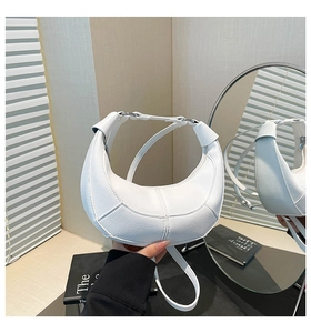 Detail view of a white half-moon shoulder bag with geometric stitching and litchi texture