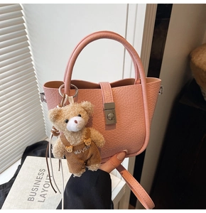 Detailed view of pink lychee grain bucket bag with cute plush bear charm and silver lock