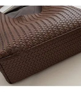 Close-up of dark brown woven leather handbag showing precision stitching and texture