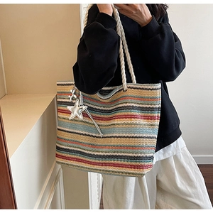 Detail of colorful striped woven tote bag featuring thick rope handles and star charm