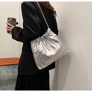 Close-up of silver quilted chain bag with gold heart and CLEAR K letter details