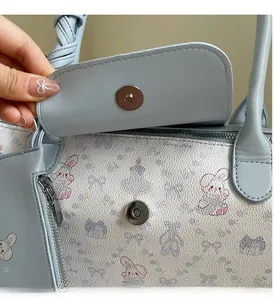 Detail of light blue crossbody bag with magnetic buckle and cartoon bunny print