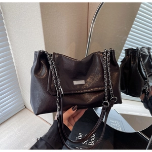 Detailed shot of textured black faux leather bag featuring a chunky silver chain strap