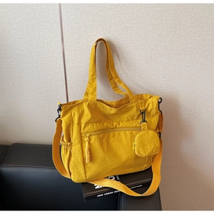 Detail of a bright yellow nylon tote bag with a small round coin purse and crossbody strap