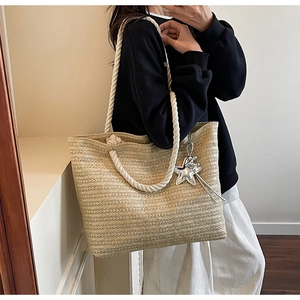 Close-up of woven straw tote bag with rope handles and star charm for summer beach vacation