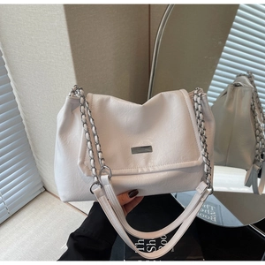 Close-up of white pleated PU leather shoulder bag with metallic chain and buckle detail