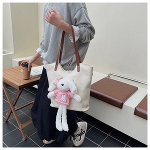 Dettaglio di una borsa tote in tela crema con un simpatico coniglietto e manici in pelle