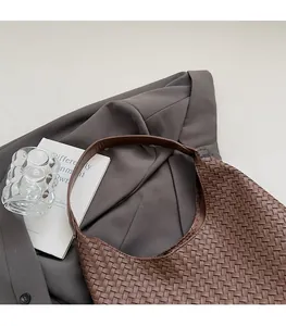 Detailed close-up of dark brown woven leather hobo shoulder bag in a refined city style