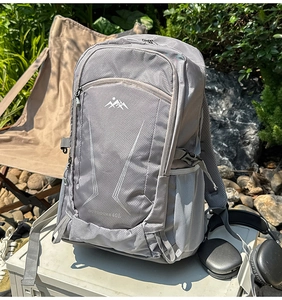 Close-up of light gray mesh backpack with side mesh pocket and outdoor gear background