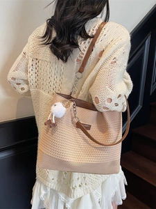 Grand sac cabas tressé beige avec bandoulières en cuir marron porté à l'épaule par mannequin