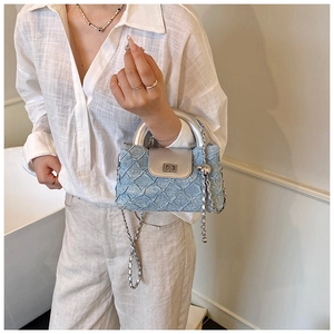 Detail der hellblauen Denim-Stepptasche mit silbernem Metallgriff und Kettenriemen