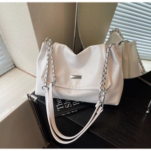 Detail of white pebbled leather shoulder bag with silver hardware and chain strap