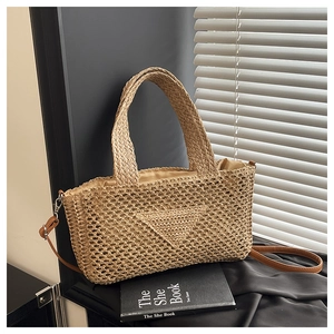 Detail of handwoven beige straw tote bag featuring triangular flap and brown leather strap
