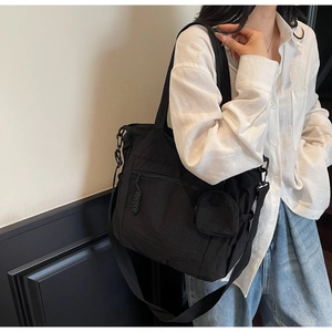 Detail of multi-pocket black canvas tote bag with adjustable strap and small round coin purse