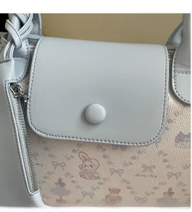 Detailed macro of a light blue PU leather tote bag with cute cartoon prints and metal zipper