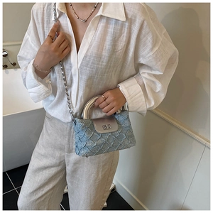 Detail einer blauen Mini-Tasche mit silbernem Ringgriff und Metallkettenriemen