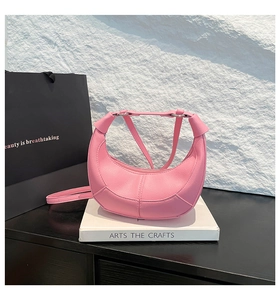 Detailed view of pink lychee textured crescent handbag on props with sleek stitching