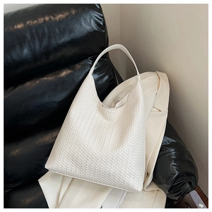 Detailed view of white woven leather hobo bag with intricate pattern on a sofa