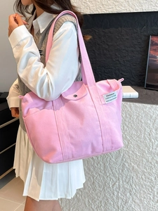 Pink canvas tote bag with side pockets and large capacity, shown on model in modern room