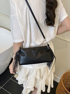 Minimalist black pleated baguette bag with long side tassels and silver hardware