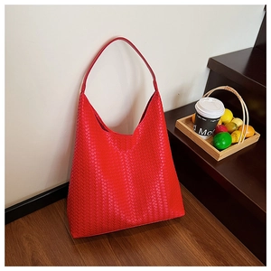 Detail of red woven leather hobo bag on stairs with coffee and fresh citrus fruits
