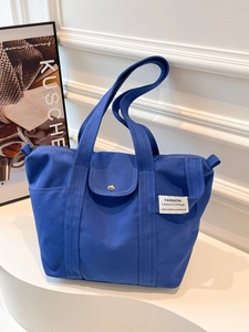 Navy blue canvas tote bag with fashion label and shoulder straps on minimalist background