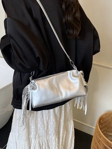 Silver metallic pleated handbag with long side tassels shown in a stylish lifestyle setting