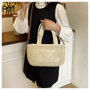 Macro detail of beige woven tote bag with triangular pattern and brown leather strap