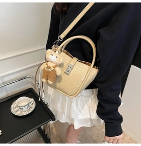 Detail of beige lychee pattern leather bucket bag with cute bear plush charm decoration