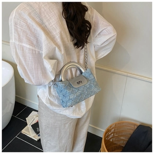 Detailsicht der hellblauen gesteppten Beuteltasche mit silbernem Metallgriff und Kette